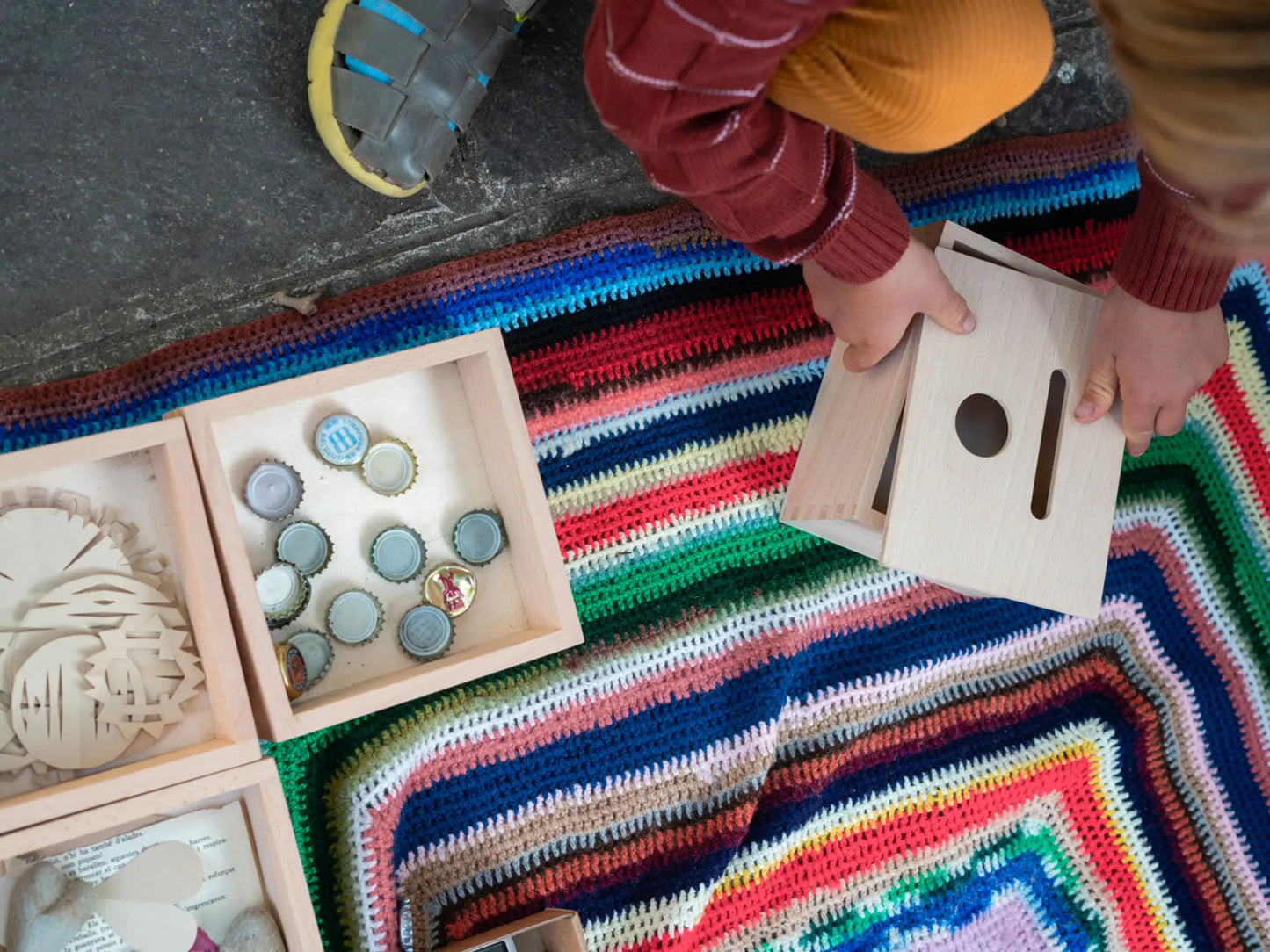 Child playing with wooden toys on a colorful rug