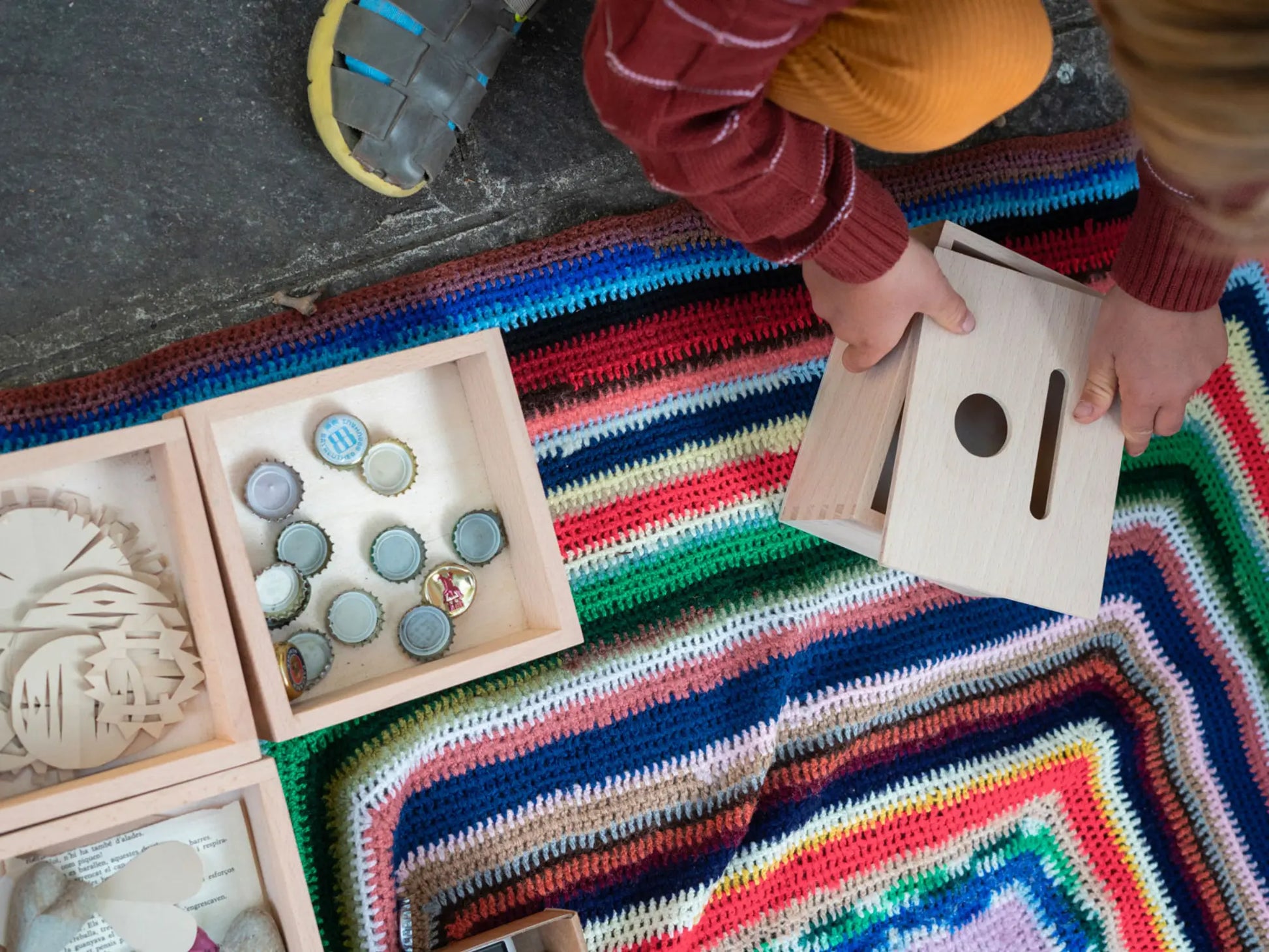 Child playing with wooden toys on a colorful rug