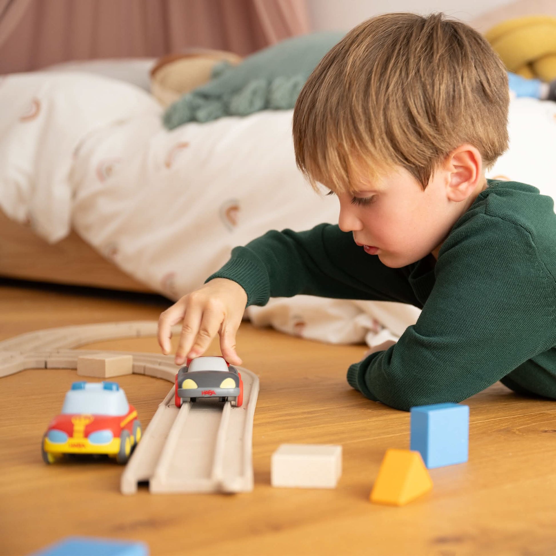Child playing with toy cars on a wooden track