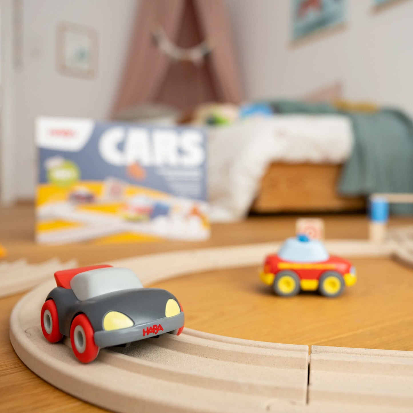 Toy cars on a wooden track with a 'CARS' book in the background