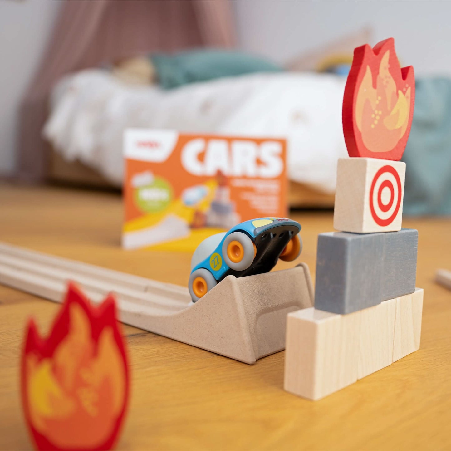Toy car on a track with wooden blocks and fire-themed elements on a wooden surface.