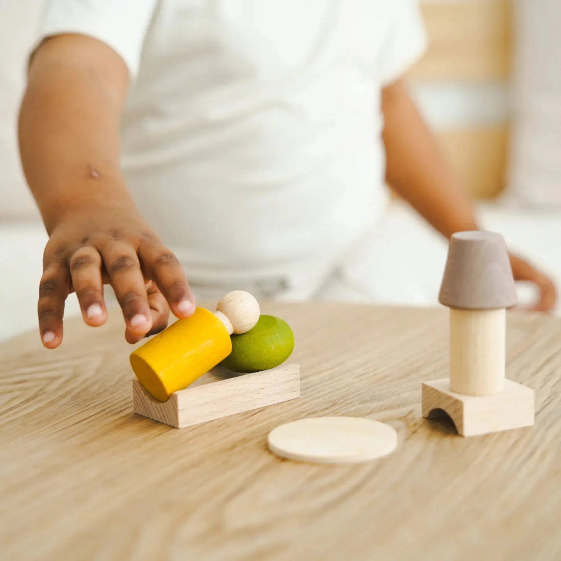 Child playing with wooden toys on a wooden surface