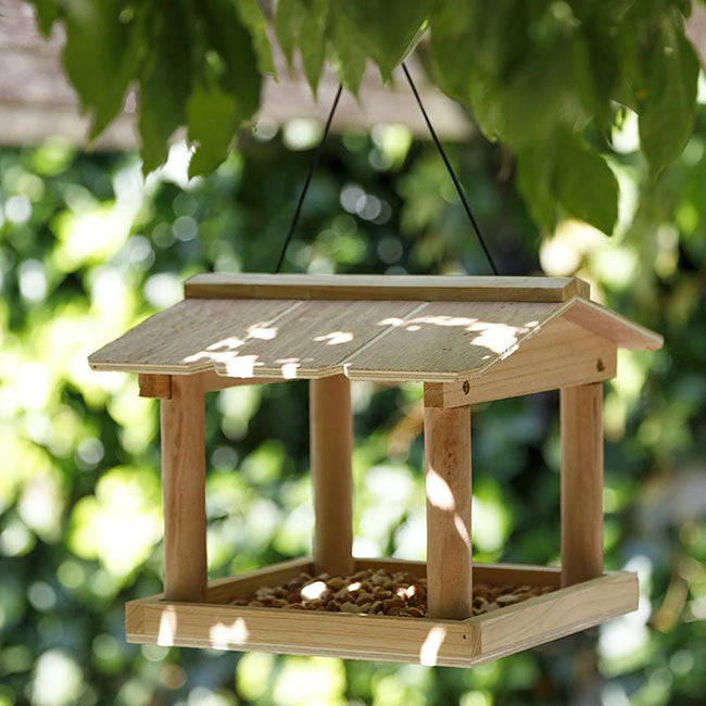 A DIY bird feeder kit made of precut wooden panels, with hardware included for assembly. The feeder is designed to be hung and has a compartment for seeds.