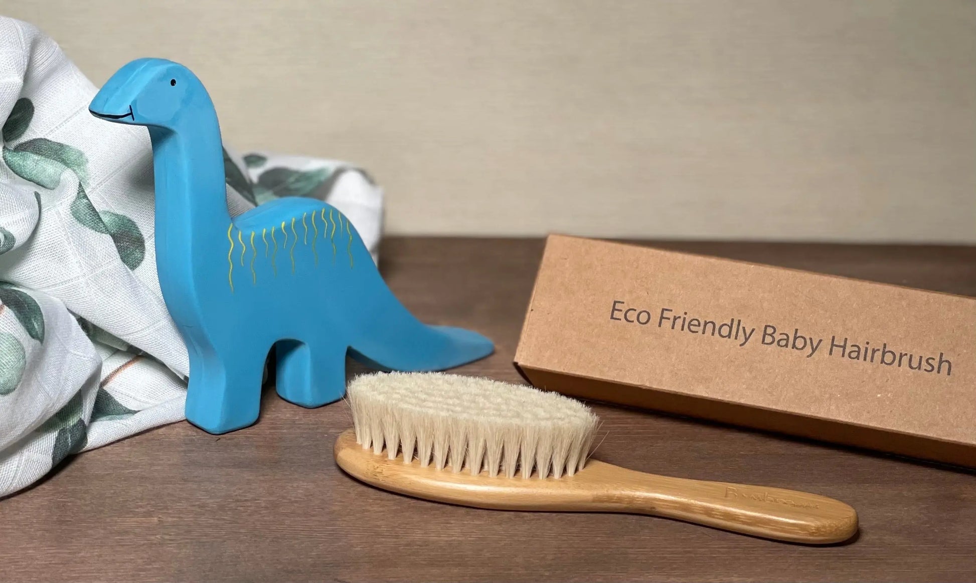 Natural Baby Brush next to a baby toy and swaddle and brush box