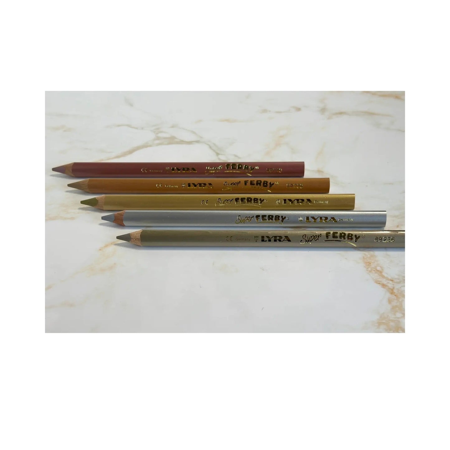 Four pencils of different colors on a marble surface