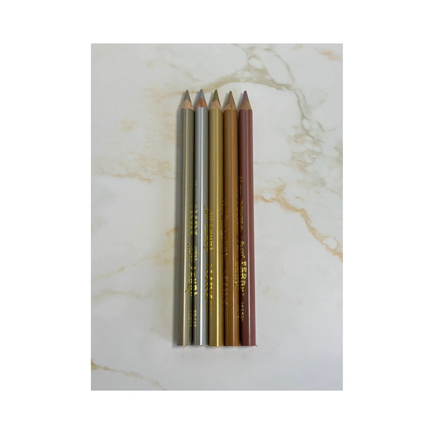 Set of five colored pencils on a marble surface