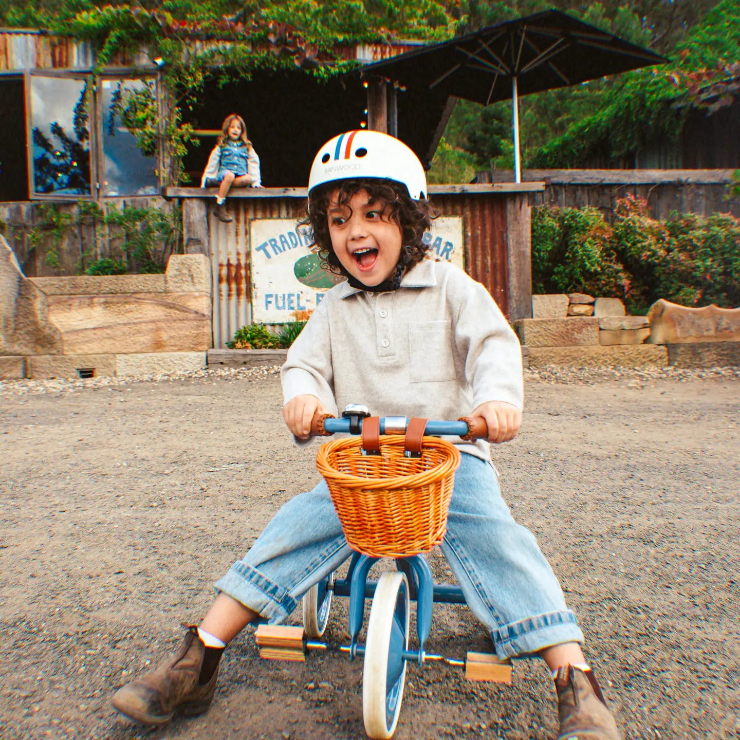 Child laughing while riding Banwood vintage trike in blue