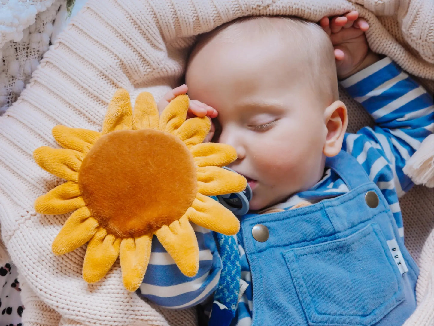 Sleeping baby hanging onto organic cotton sunflower crinkle toy