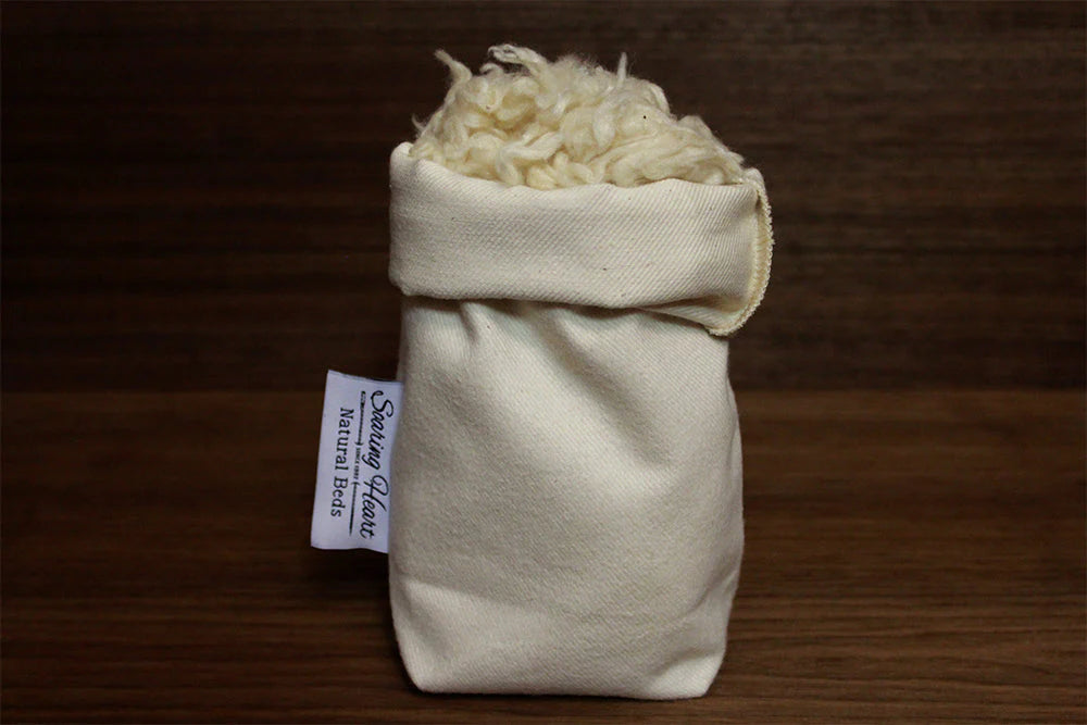 Small bag of kapok natural stuffing material with a label on a wooden surface