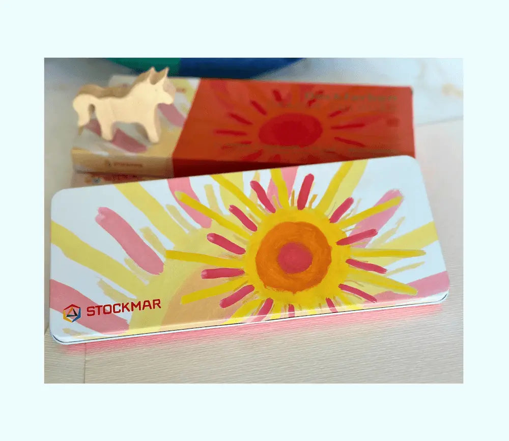 Colorful rectangular object with sun design and 'Stockmar' branding on a light background