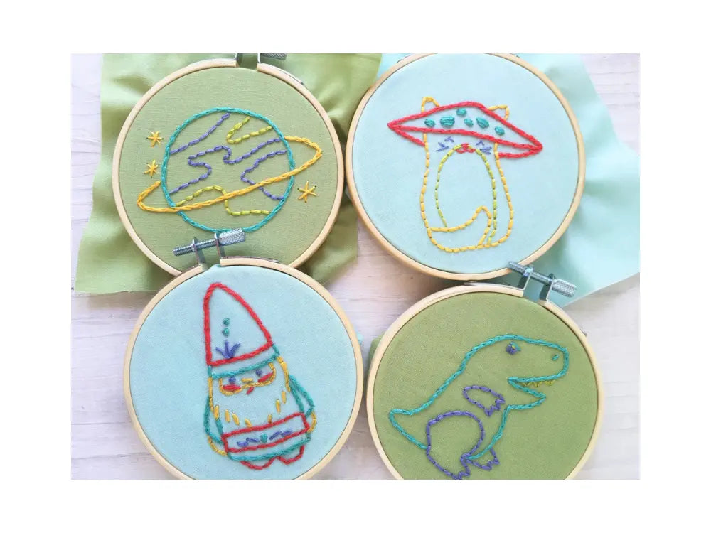 Four embroidery hoops with space-themed designs on a light green background