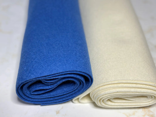 Rolls of blue and white large wool felt sheets on a light background