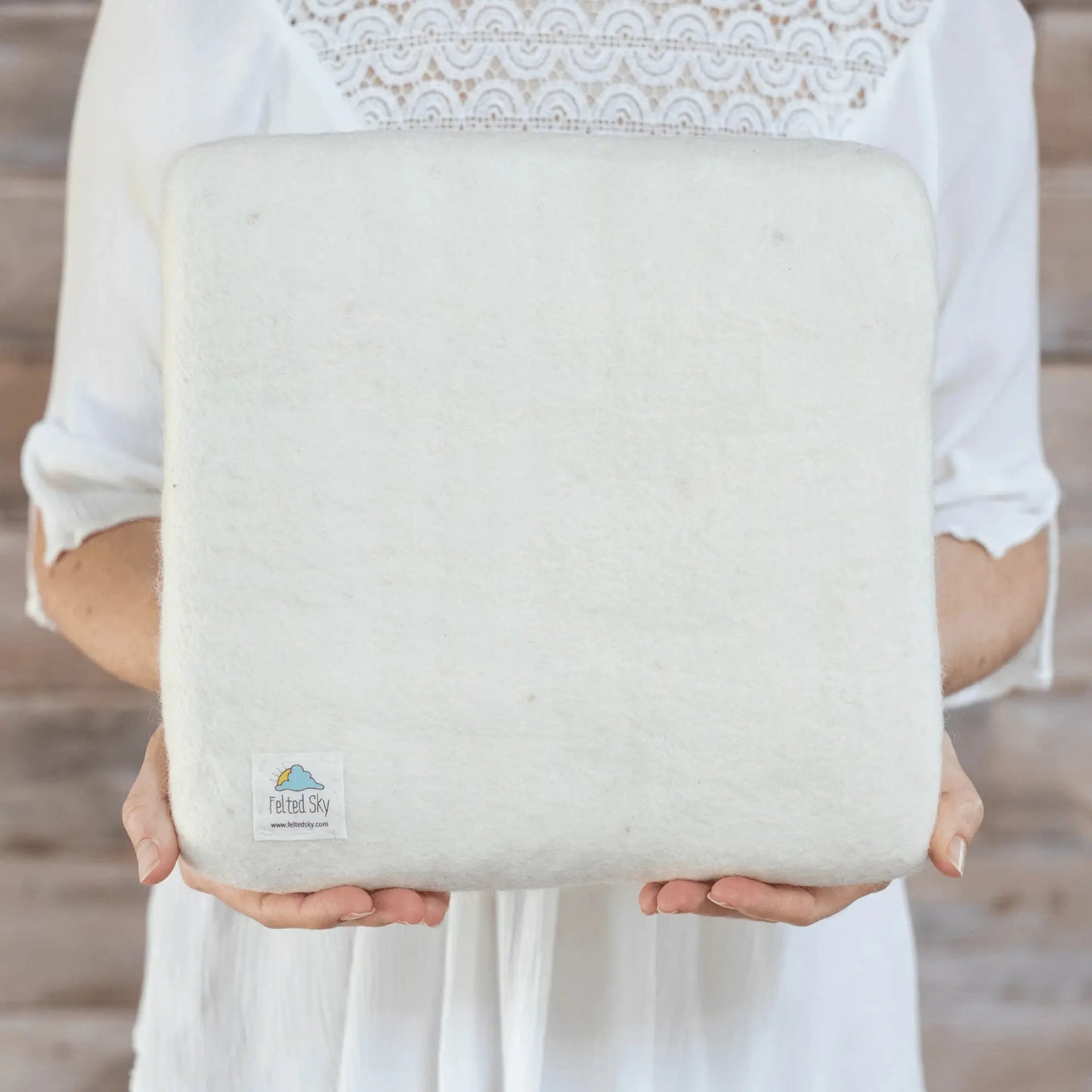 Person holding a large needle felting mat with a visible brand logo against a neutral background