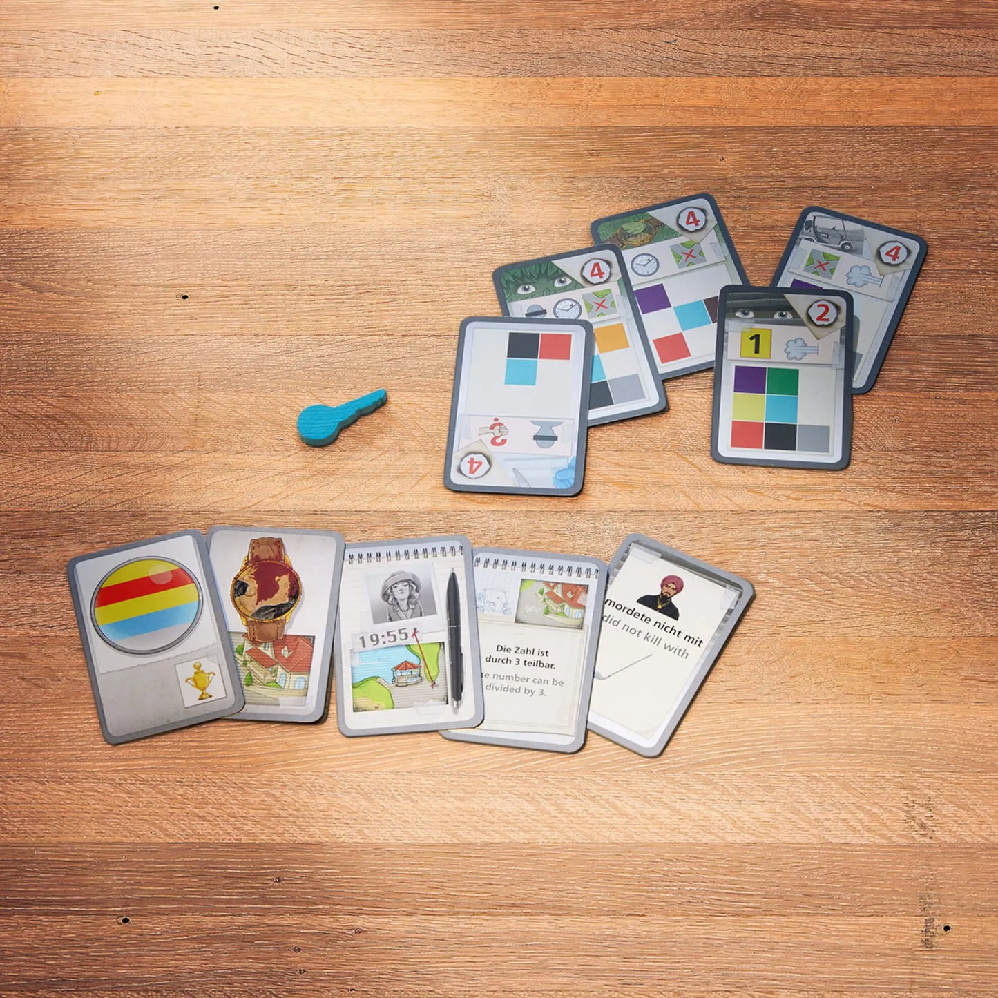 Collection of playing cards from HABA mystery deduction game called The Key and a blue key on a wooden surface