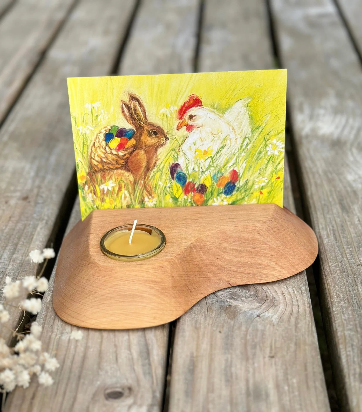 An Easter postcard of a bunny and a hen with colorful eggs in a candle stand on a rustic table