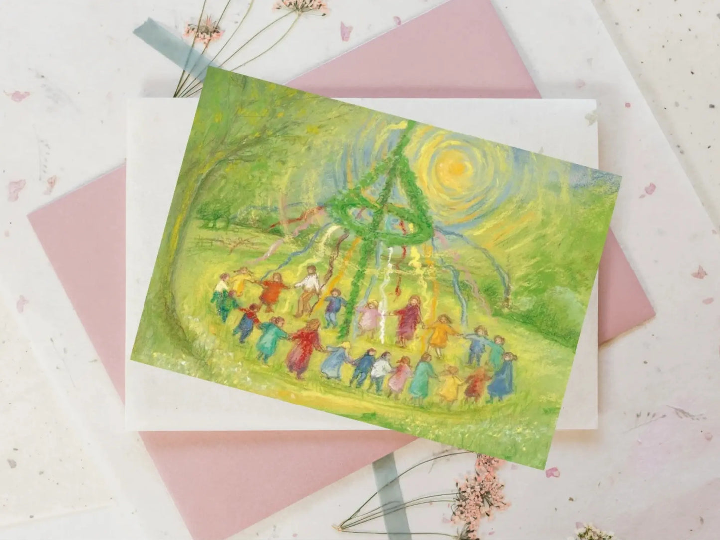 Colorful illustration of people celebrating Mayday with a Maypole on a card with pink envelope.