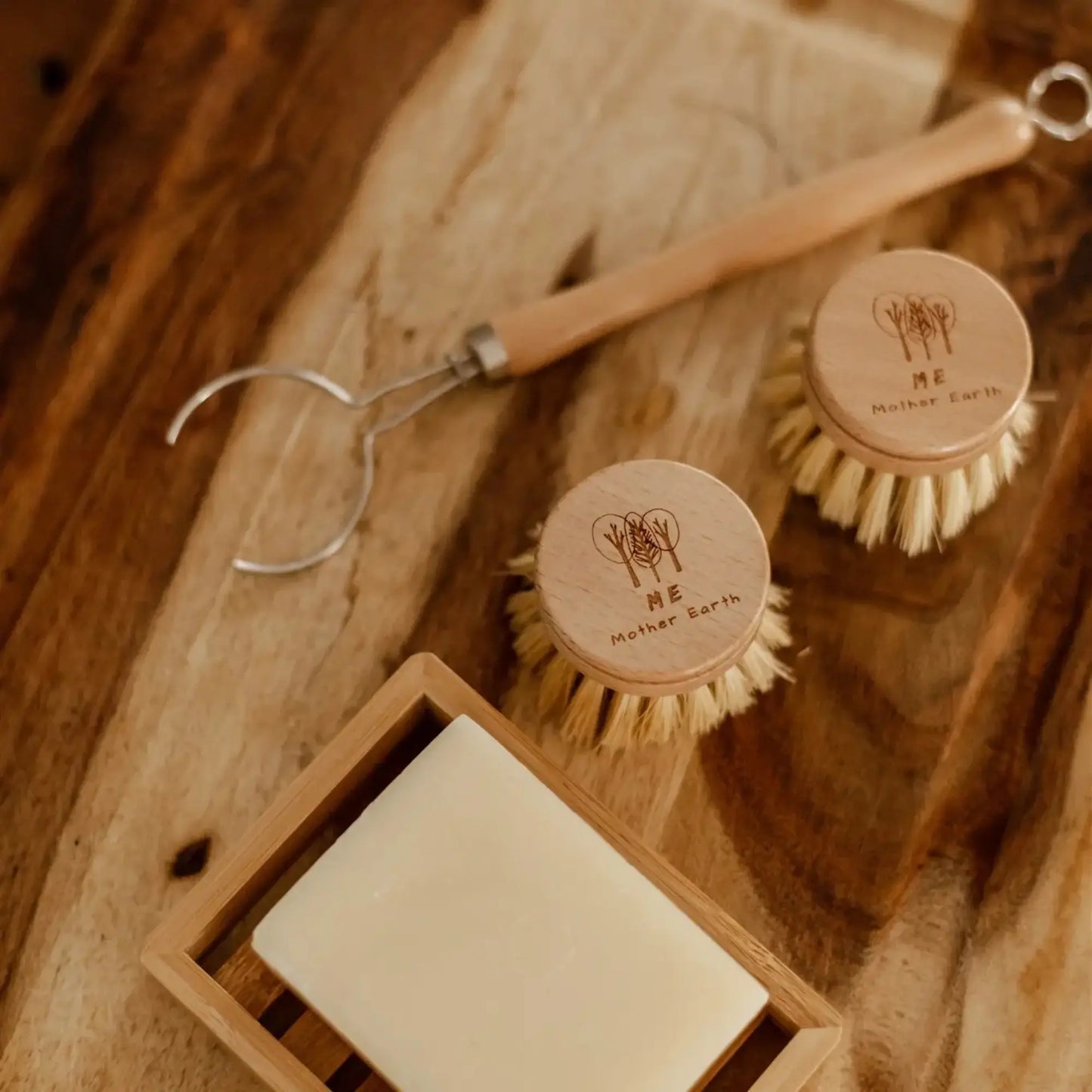 Cleaning brushes and soap on a wooden surface with 'Mother Earth' branding.