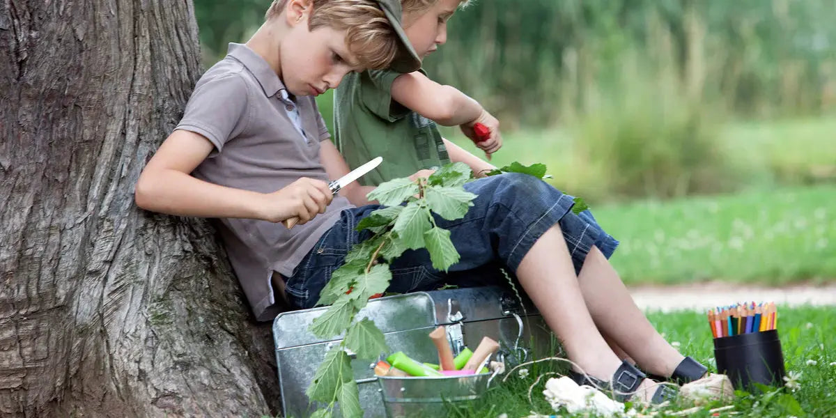 Two kids using Opinel No. 7 Junior Folding Pocket Knife sitting up against a tree