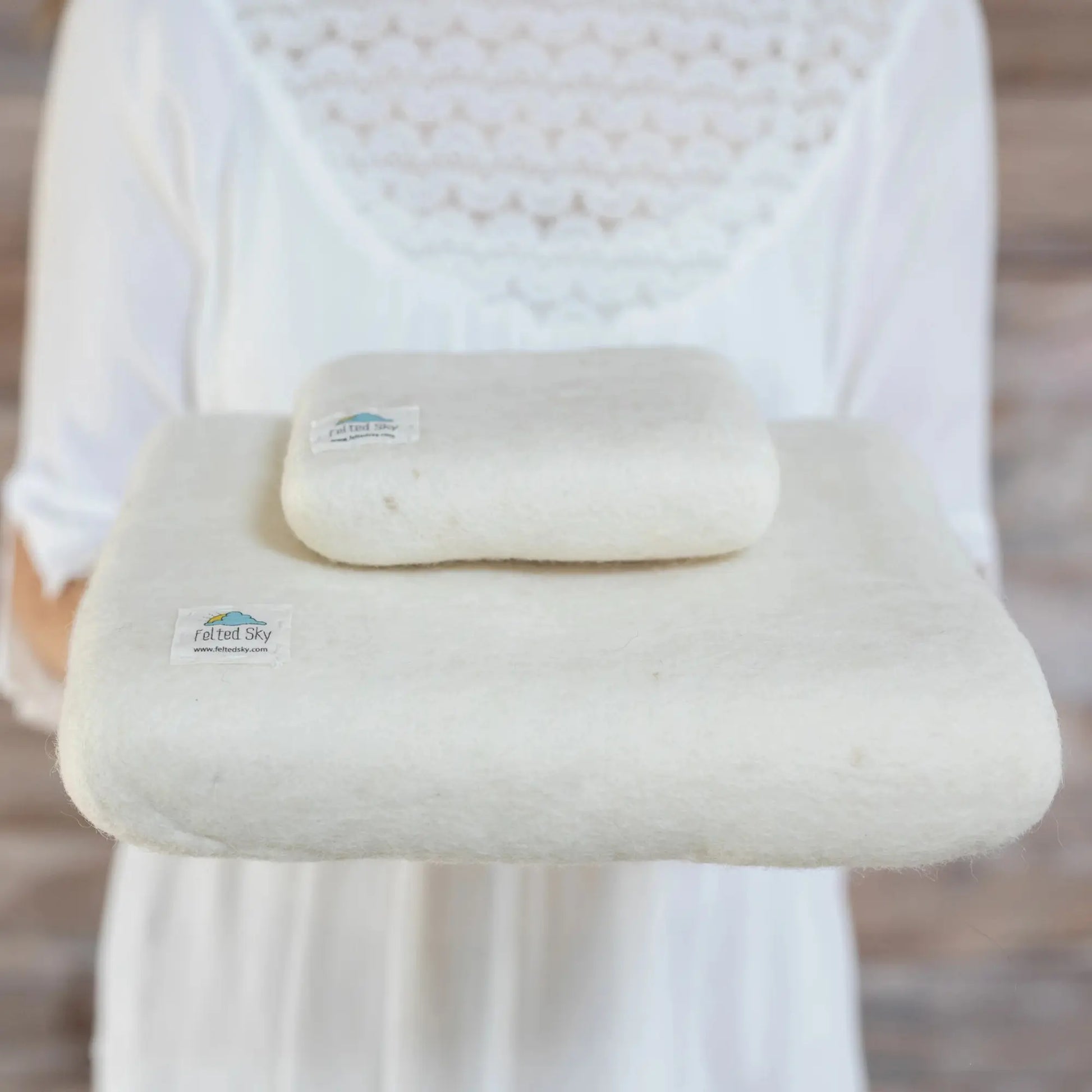 Person holding a large needle felting mat made from wool with visible logo