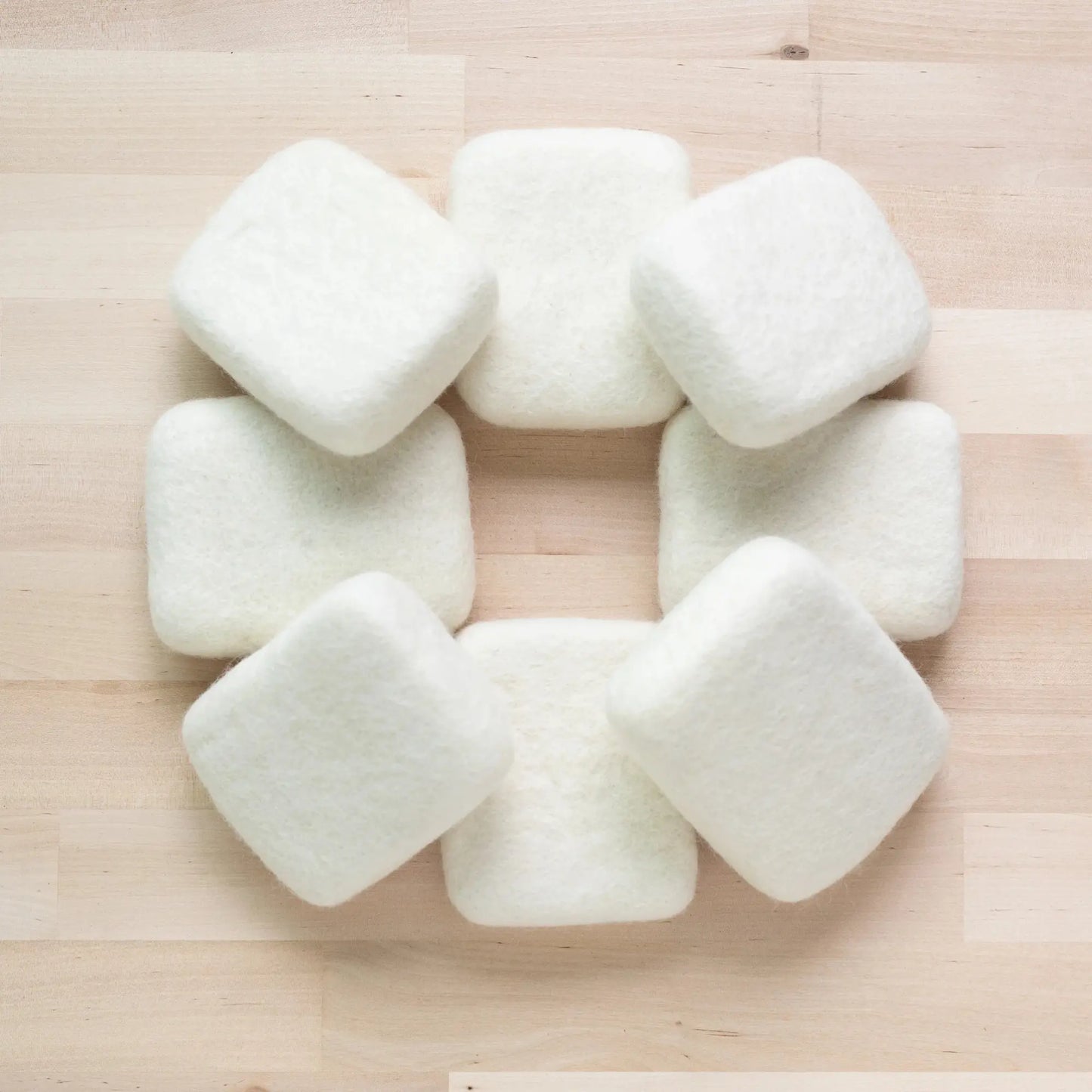 A circle of pocket sized needle felting mats on wooden background