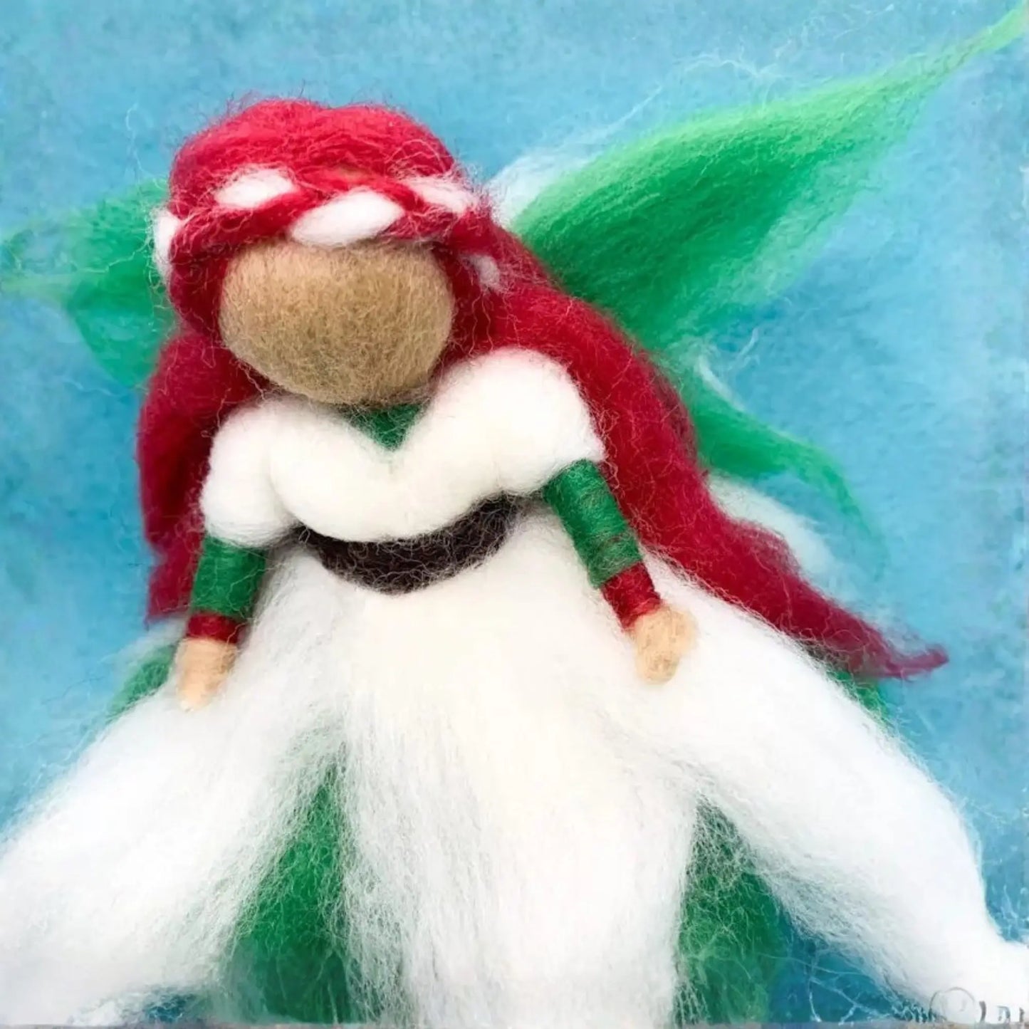 Handmade fairy figurine with red hair and a white dress on a blue background