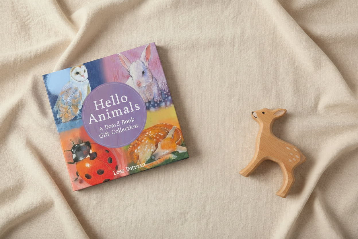 Gift box cover of 'Hello Animals' with illustrations of an owl, rabbit, ladybug, and deer on a muslin cream cloth with a wooden deer toy next to it