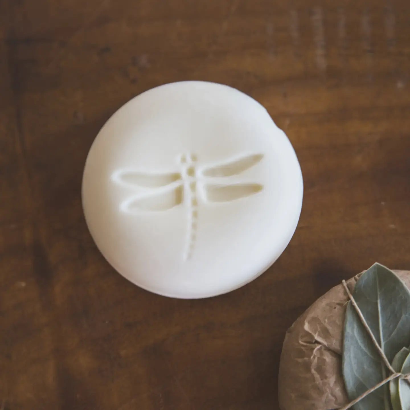 White olive oil soap with a dragonfly design on a wooden surface
