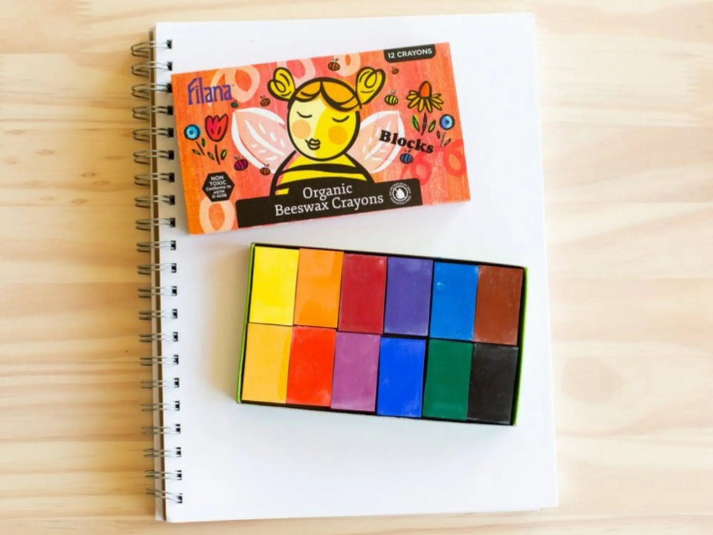 Set of organic beeswax crayons on a notebook with packaging displayed.