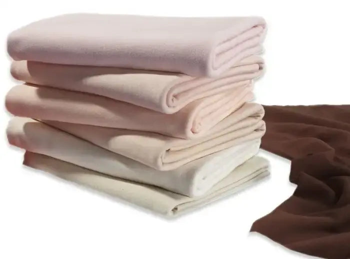 Stack of folded organic cotton doll making fabric with a brown sheet on the side against a white background