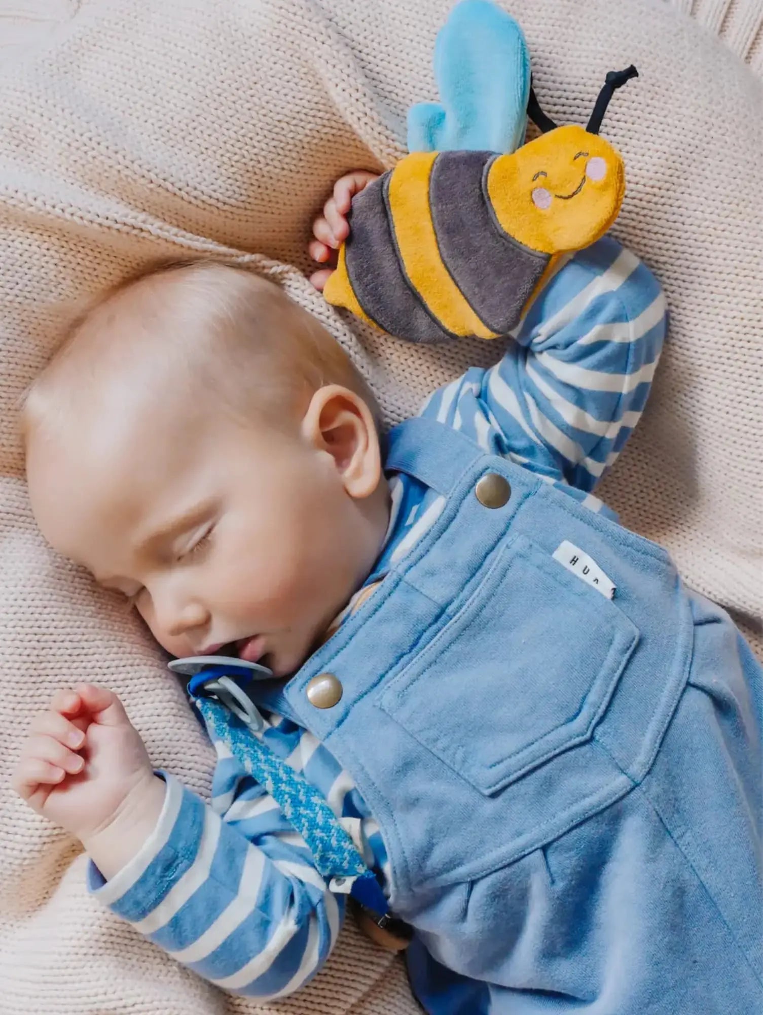 Sleeping infant with honeybee-shaped crinkle toy in hand