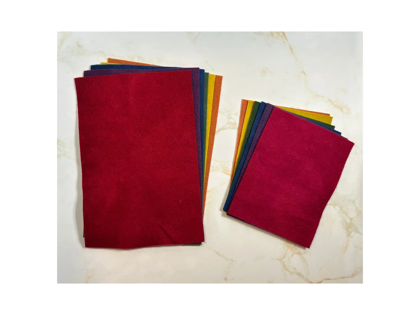 Stack of colorful wool felt fabric sheets on a marble surface