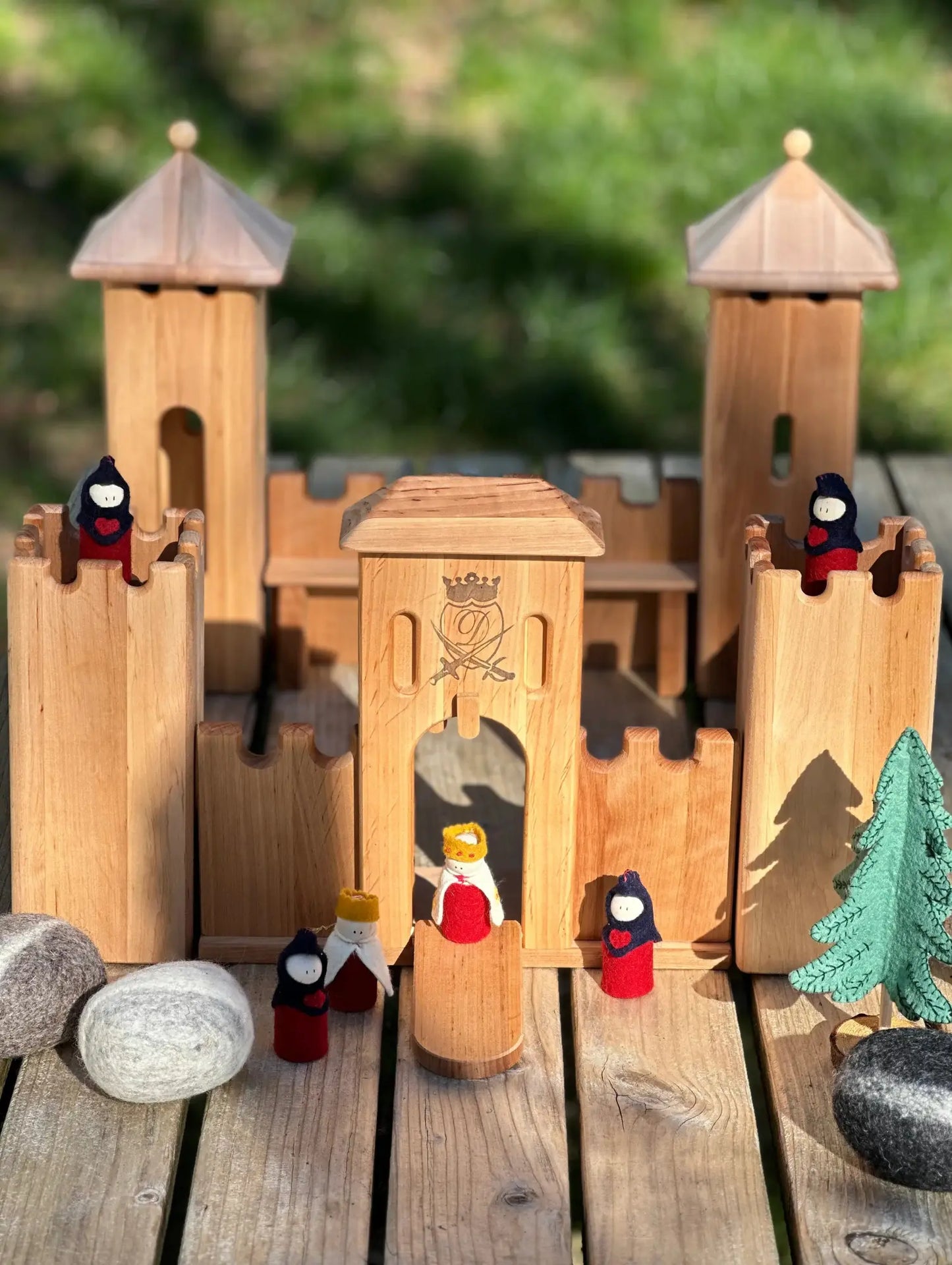 Wooden toy castle with small figurines on a wooden surface