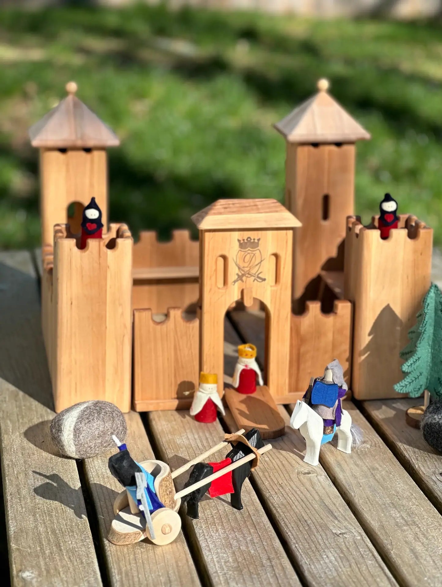 Wooden toy castle with small figures on a wooden surface outdoors
