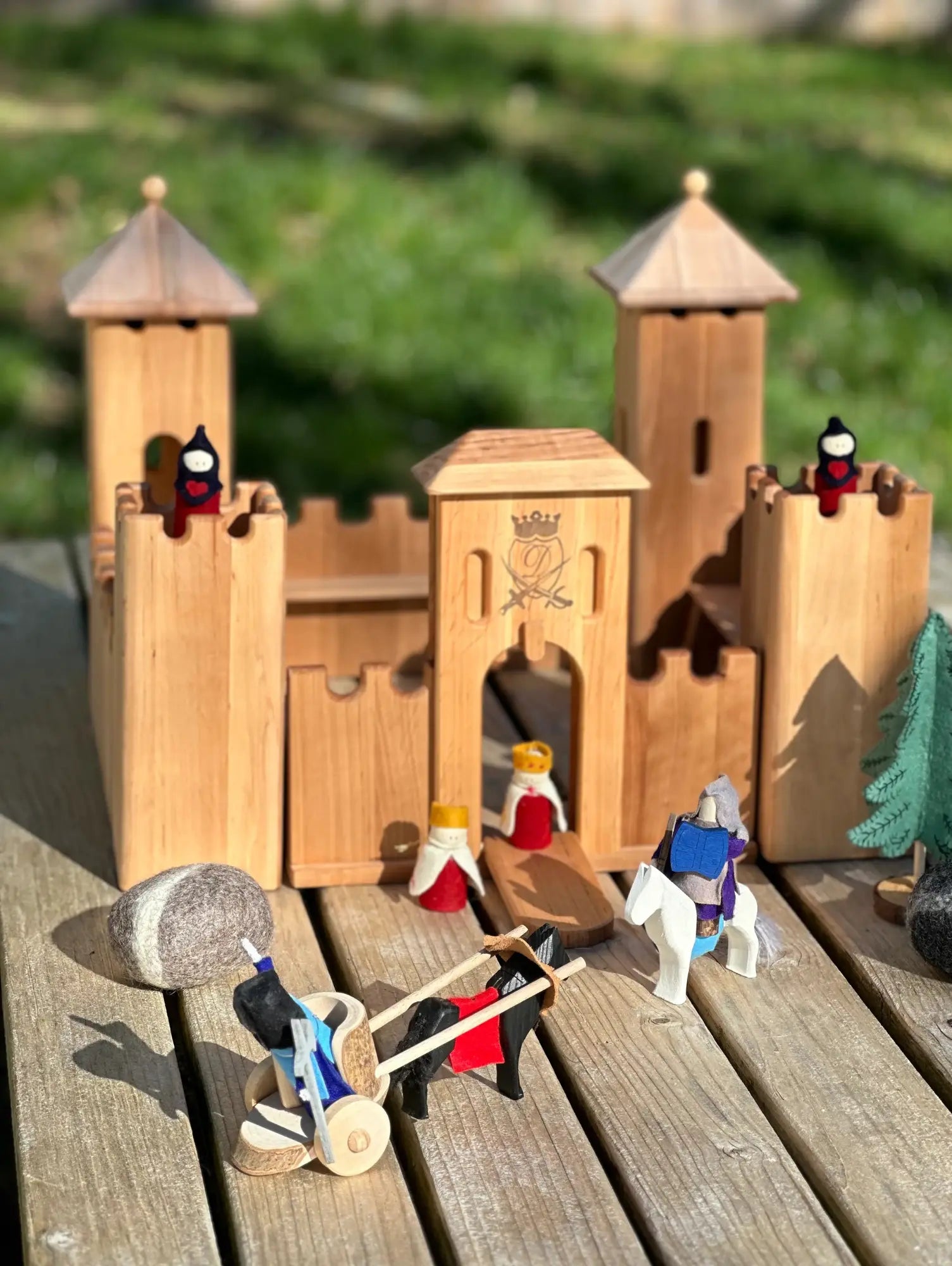 Wooden toy castle with small figures on a wooden surface outdoors