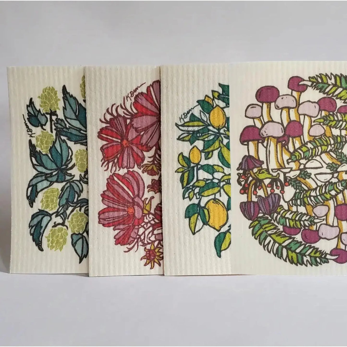 Set of four decorative Swedish dishcloths with floral and nature-themed designs on a light gray 