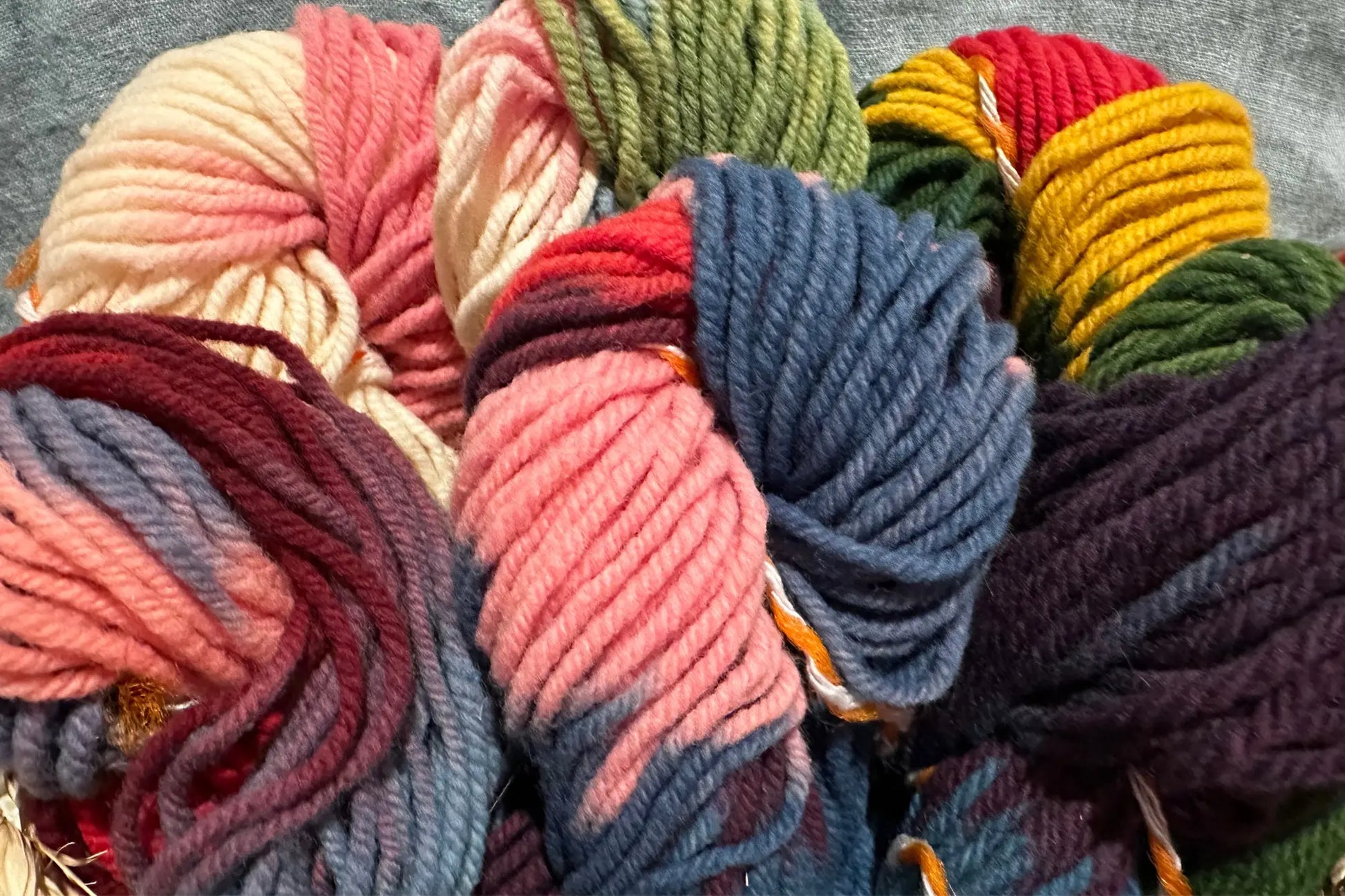 Assorted colorful yarn balls on a textured surface