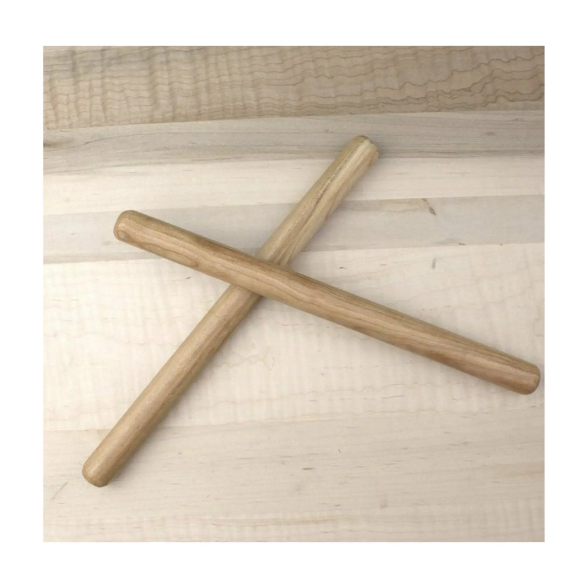 Two Wooden Rhythm sticks made from cherrywood hardwood criss crossed on a tabletop
