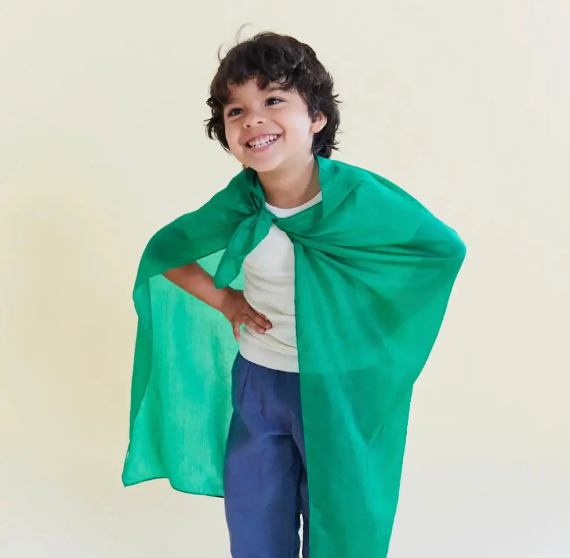 Boy smiling with emerald green playsilk tied on as a cape