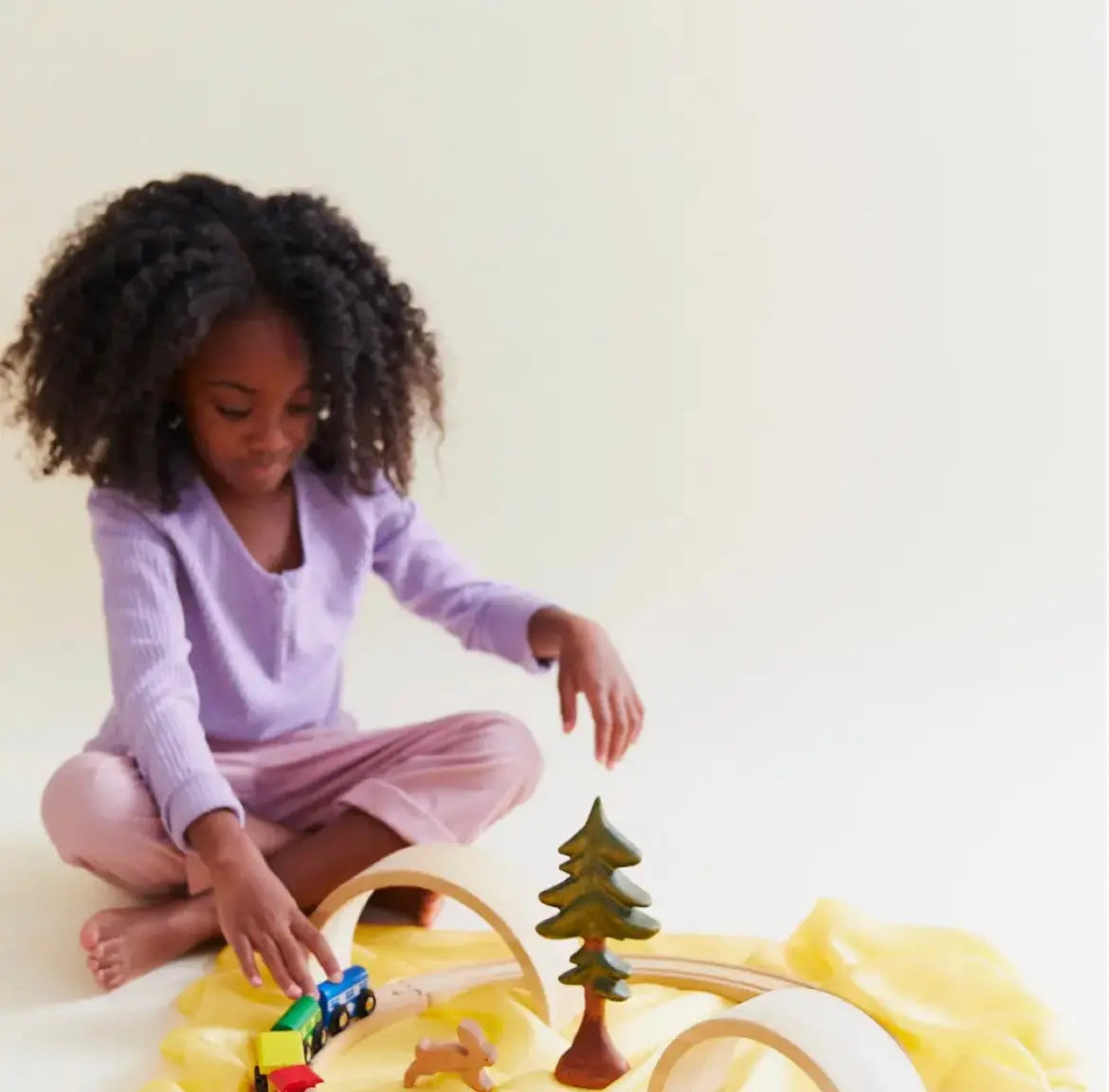 Girl playing with a train and arches on top of a yellow playsilk