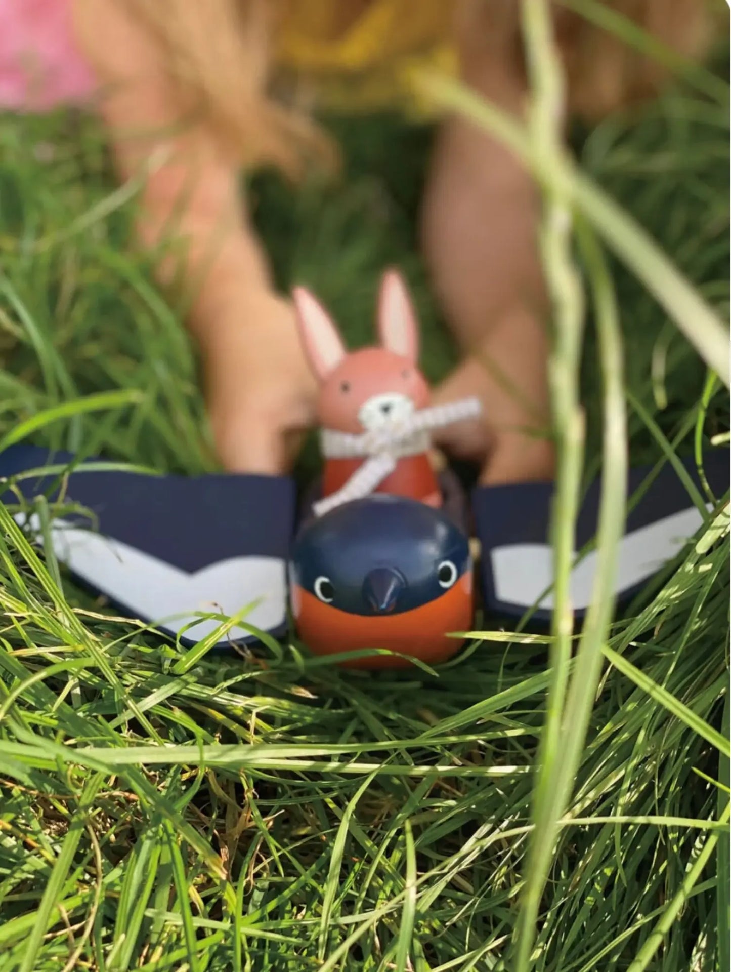Child holding Tenderleaf Toys Swifty Bird and Hare in the grass