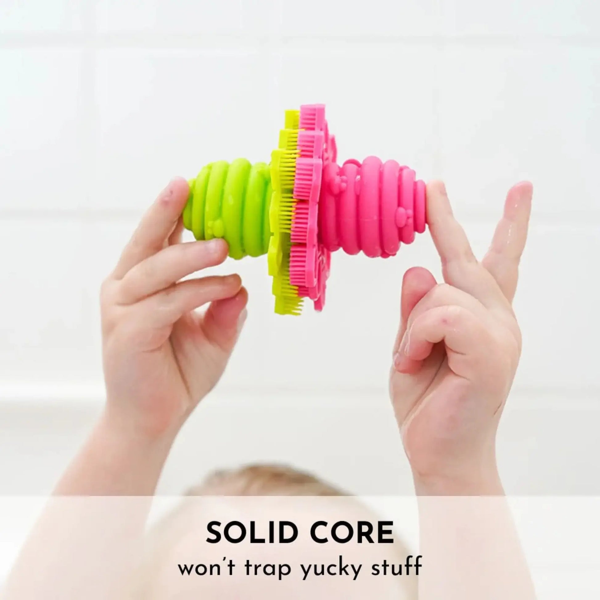 Child holding up a green and pink scrubby with text that says solid core - won't trap yucky stuff