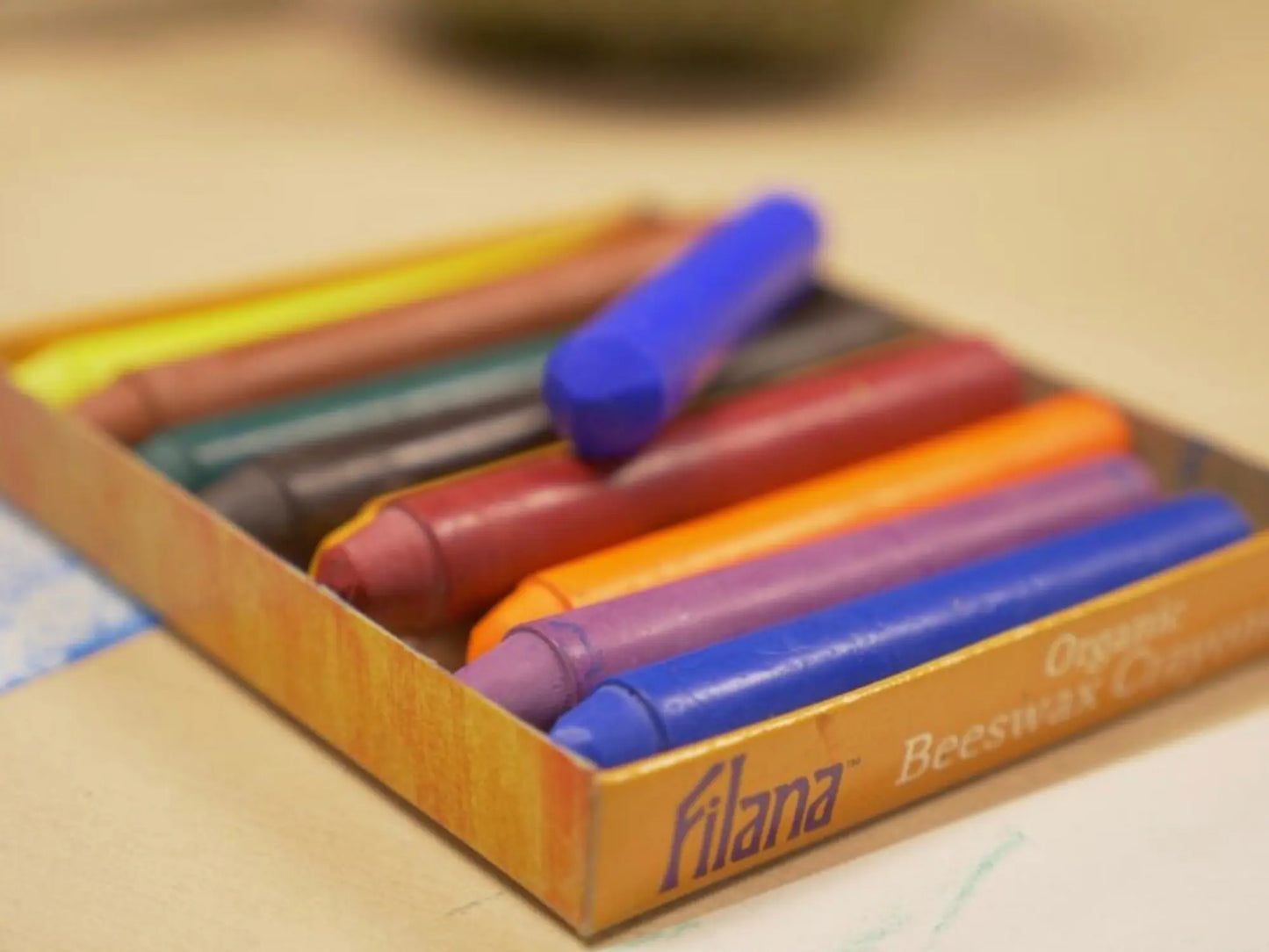 Box of colorful crayons with 'Filana' branding on a blurred background