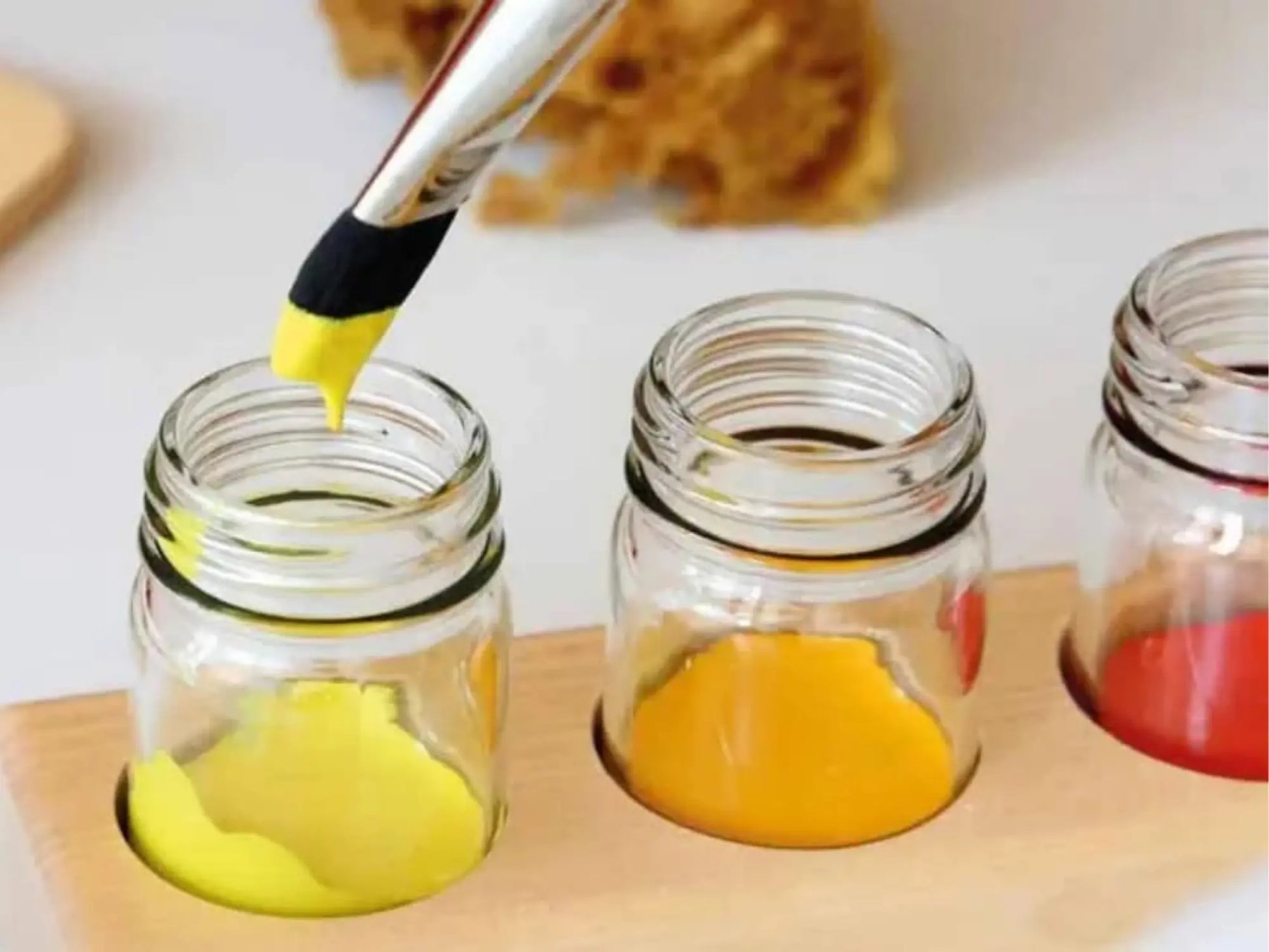 Yellow substance being poured into a glass jar on a wooden surface.