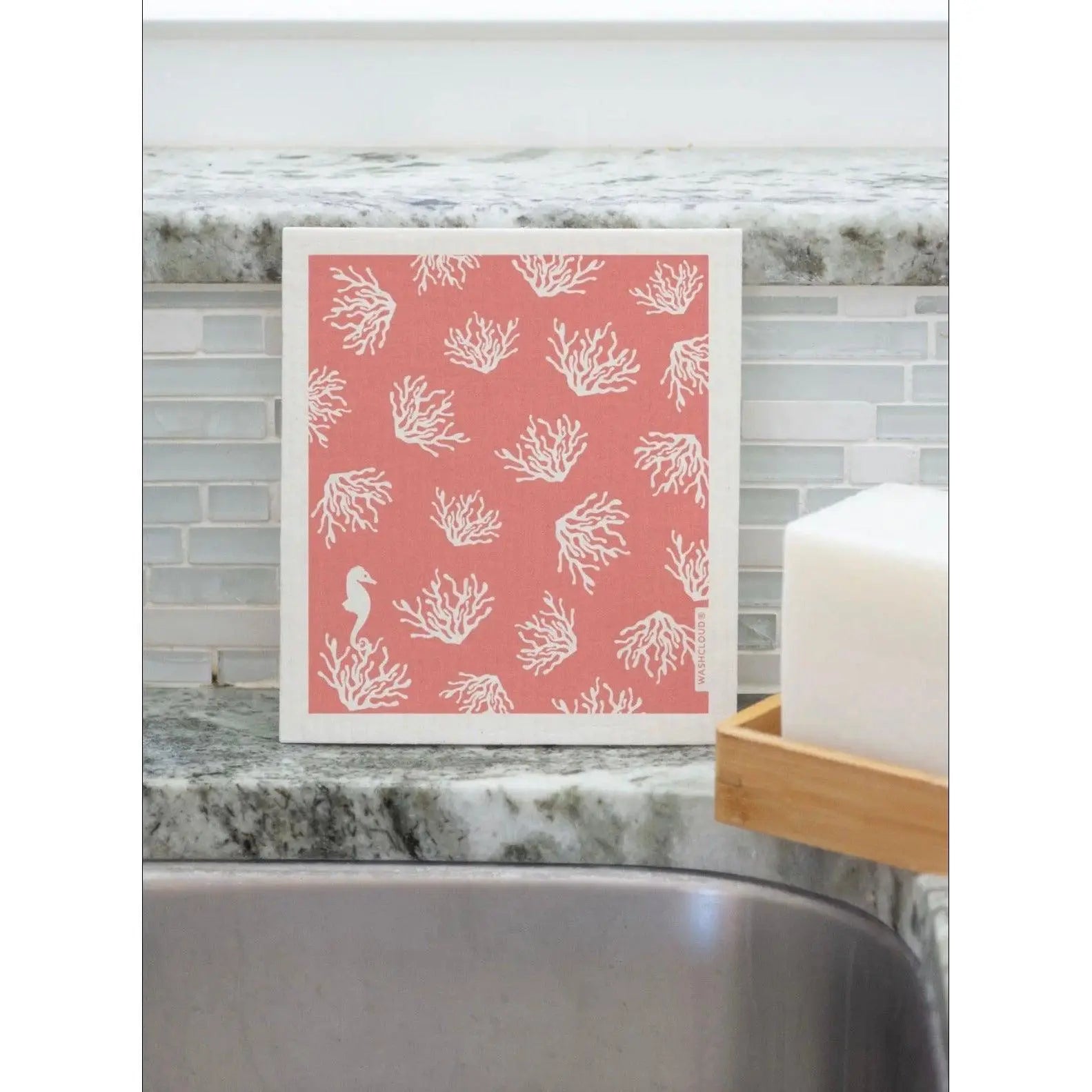 Swedish Dishcloth in peach and white with coral design propped in a kitchen