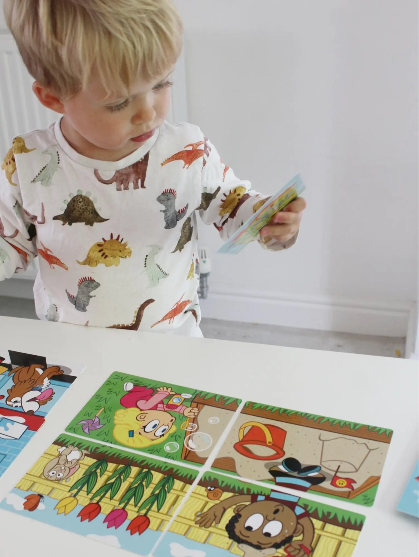 Child playing with a puzzle featuring cartoon characters on a white surface.