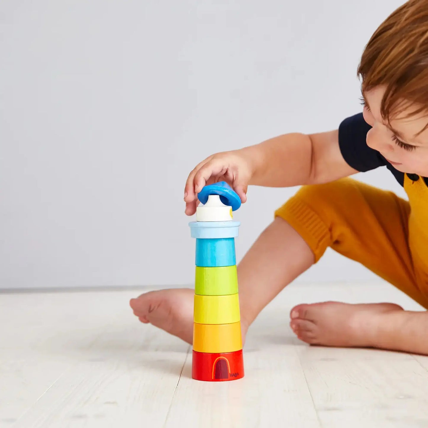 Child playing with a colorful stacking toy on a light background