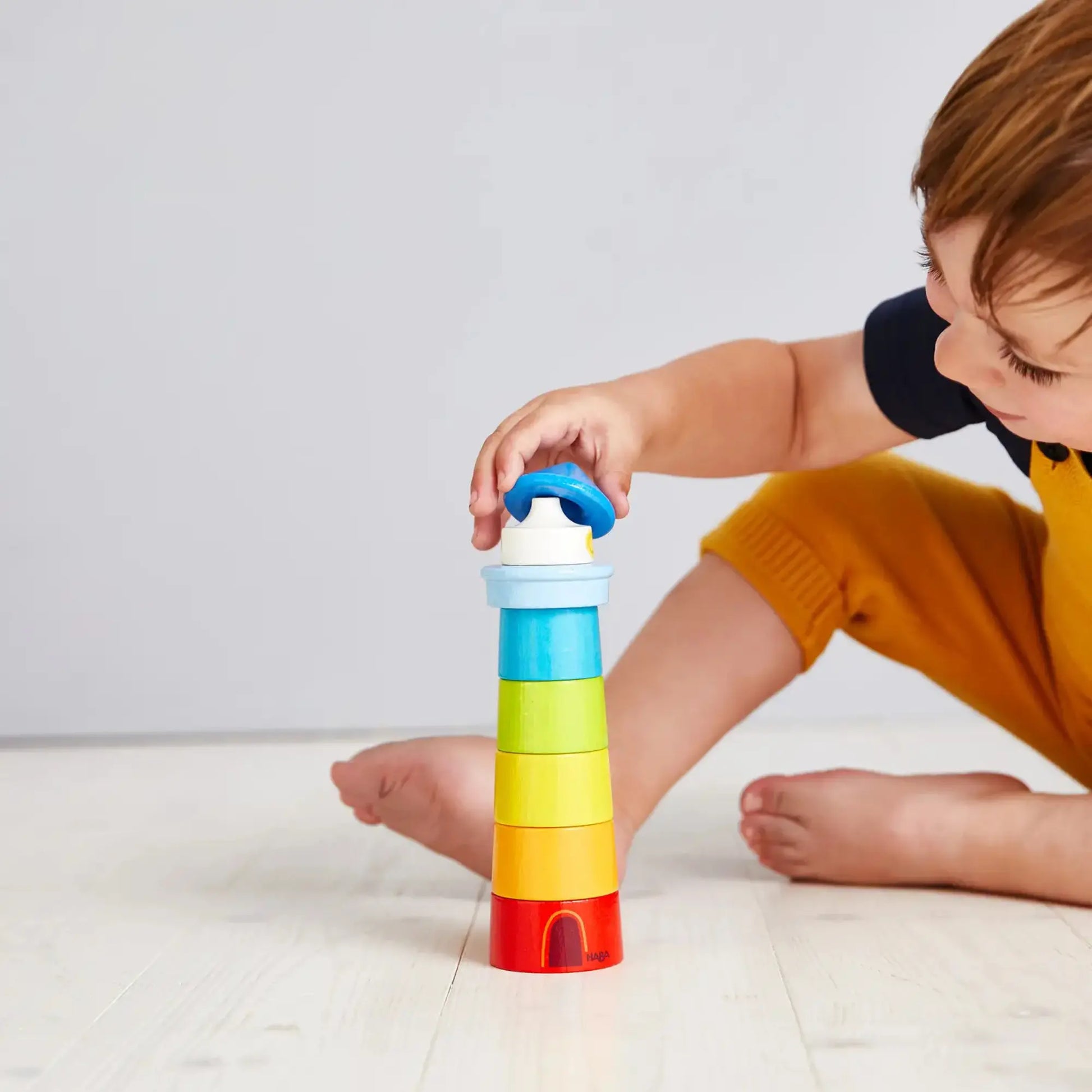 Child playing with a colorful stacking toy on a light background