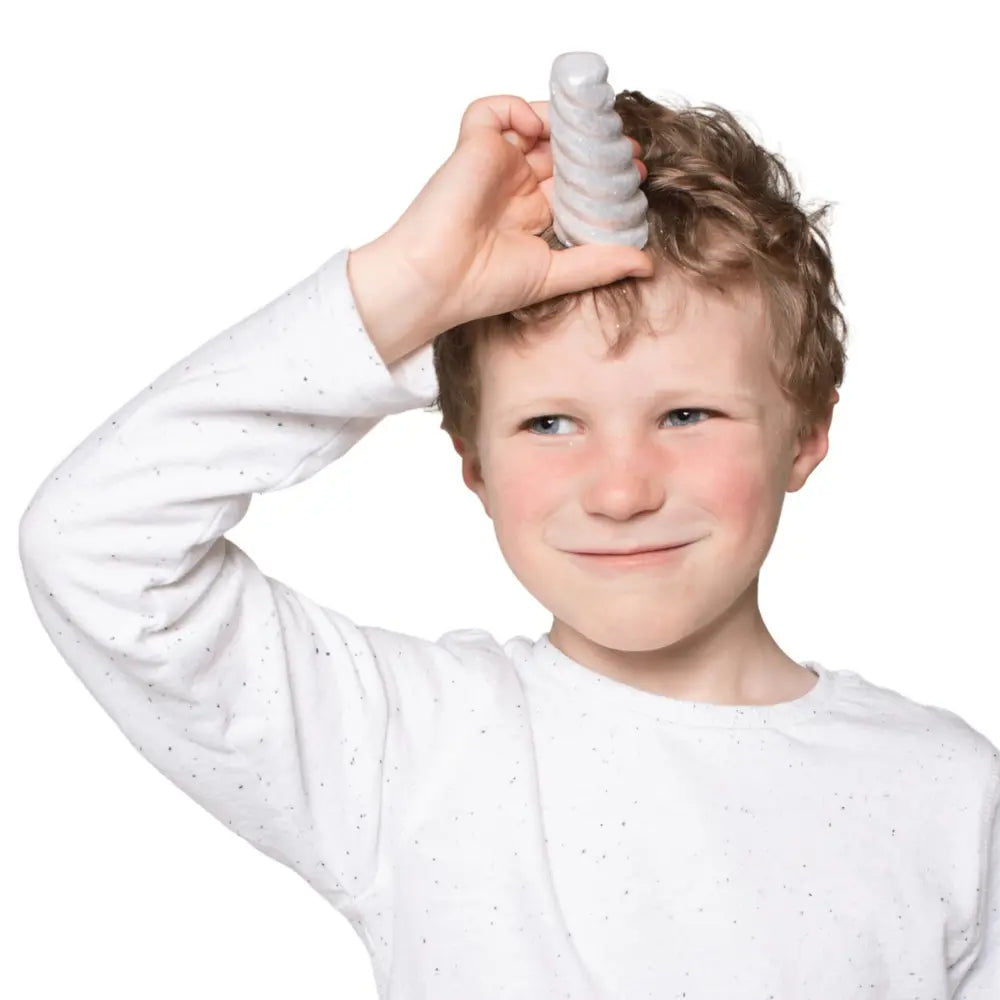Child holding a piece of silver sparkly narwhal horn sidewalk chalk on a white background