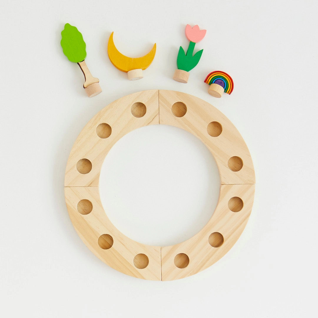Wooden birthday ring with holes and small colorful wooden figures on a light gray background