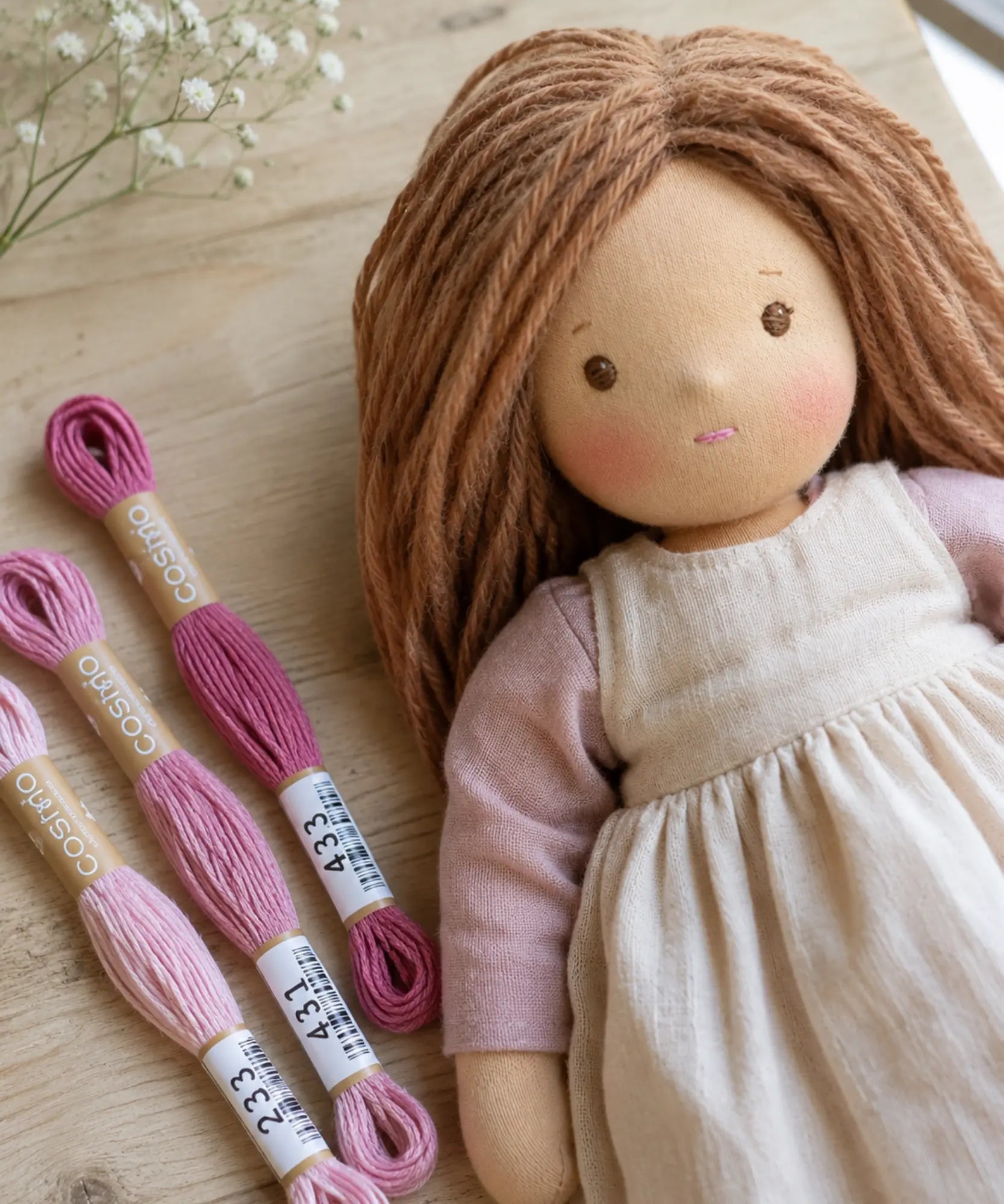 Waldorf doll with pink lips using pink floss next to her lifestyle scene